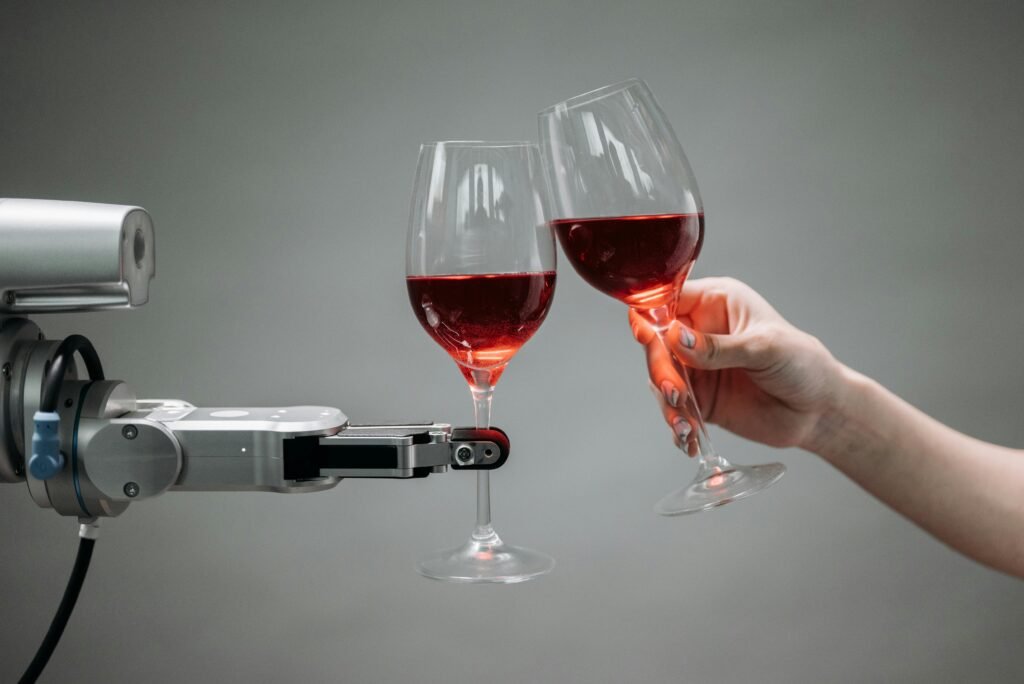 AI Tools for Real Results A robot and a human hand clinking glasses of red wine, symbolizing AI tools, technology and celebration.